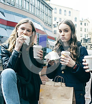 Lifestyle and people concept: two girls and guy eating fast food on city street together having fun, drinking coffee