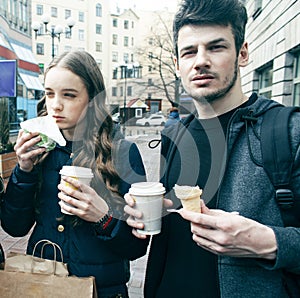 Lifestyle and people concept: two girls and guy eating fast food on city street together having fun, drinking coffee