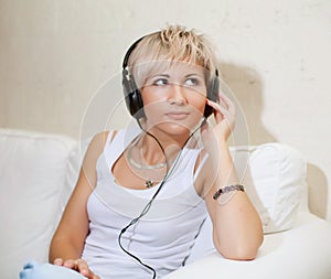 Woman in living room listening to MP3 player smiling