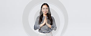 Lifestyle, people emotions and casual concept. Cute asian girl in casual outfit smiling as saying namaste, holding hands