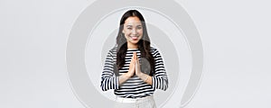 Lifestyle, people emotions and casual concept. Cute asian girl in casual outfit smiling as saying namaste, holding hands