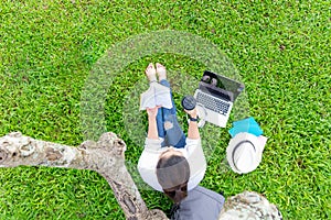 Lifestyle person Girl enjoy reading a book and play laptop on the grass field of the nature park