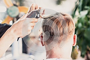 Lifestyle photo barbershop. Young man customer wears face mask, side back rear view. Hairdresser male hand work move