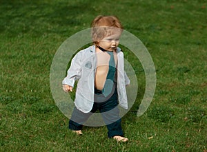 Lifestyle portrait baby child in happines at the outside in the meadow. Happy baby boy learning to walk on grass