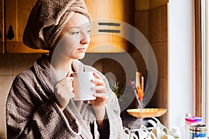 Lifestyle portrait of a beautiful young girl drinking morning coffee in her kitchen