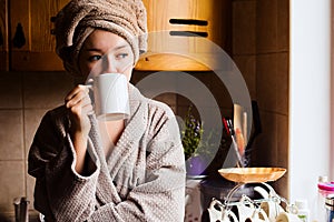 Lifestyle portrait of a beautiful young girl drinking morning coffee in her kitchen