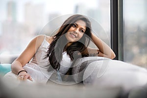 Lifestyle portrait of a beautiful young indian woman, relaxing at home in urban apartment