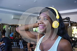 Lifestyle portrait at gym of young happy and attractive afro American woman training cheerful at fitness club listening to music w