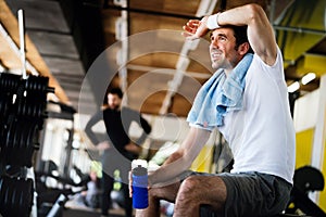 Lifestyle portrait of handsome muscular man after the training in the sport gym