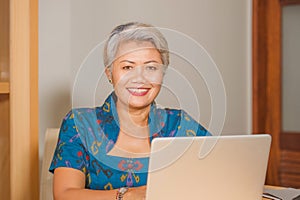 Lifestyle portrait of Happy and attractive elegant middle aged Asian business woman working smiling at office computer desk