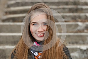 Lifestyle portrait of happy smiling young and pretty adult woman with gorgeous long hair posing in city park with shallow depth of