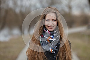 Lifestyle portrait of happy smiling young and pretty adult woman with gorgeous long hair posing in city park with shallow depth of