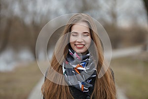 Lifestyle portrait of happy smiling young and pretty adult woman with gorgeous long hair posing in city park with shallow depth of