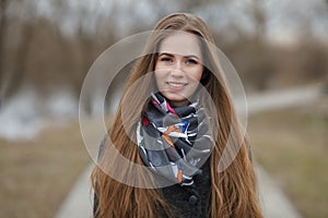 Lifestyle portrait of happy smiling young and pretty adult woman with gorgeous long hair posing in city park with shallow depth of