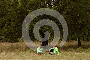 Lifestyle portrait of happy woman and man in sports uniform hiking, have a rest in autumn forest at sunny day, outdoors