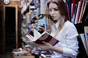 Lifestyle portrait of a lovely student girl in vintage library or bookstore