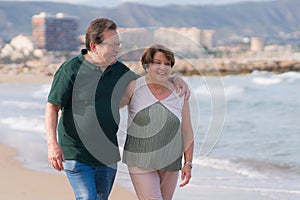 Lifestyle portrait of loving happy and sweet mature couple - senior retired husband and wife on 70s enjoying beach walk relaxed