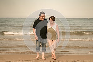 Lifestyle portrait of loving happy and sweet mature couple - senior retired husband and wife on 70s enjoying beach walk relaxed