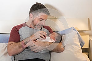 Lifestyle portrait of proud happy man holding tenderly bottle feeding her child - an adorable and beautiful newborn baby girl in