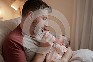 Lifestyle portrait of proud happy man holding tenderly bottle feeding her child - an adorable and beautiful newborn baby girl in