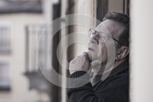 Lifestyle portrait of sad and depressed mature man 65 to 70 years old at home balcony feeling lonely and confused facing getting