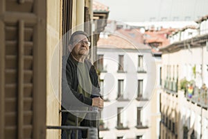 Lifestyle portrait of sad and depressed mature man 65 to 70 years old at home balcony feeling lonely and confused facing getting