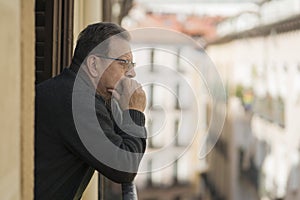 Lifestyle portrait of sad and depressed mature man 65 to 70 years old at home balcony feeling lonely and confused facing getting