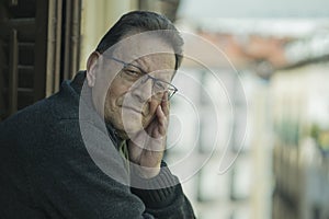 Lifestyle portrait of sad and depressed mature man 65 to 70 years old at home balcony feeling lonely and confused facing getting