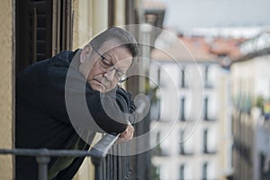 Lifestyle portrait of sad and depressed mature man 65 to 70 years old at home balcony feeling lonely and confused facing getting