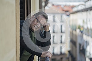 Lifestyle portrait of sad and depressed mature man 65 to 70 years old at home balcony feeling lonely and confused facing getting