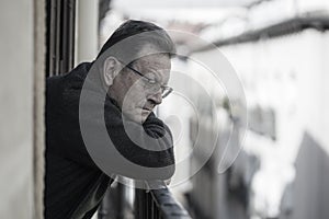 Lifestyle portrait of sad and depressed mature man 65 to 70 years old at home balcony feeling lonely and confused facing getting