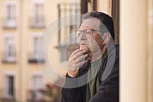 Lifestyle portrait of sad and depressed mature man 65 to 70 years old at home balcony feeling lonely and confused facing getting