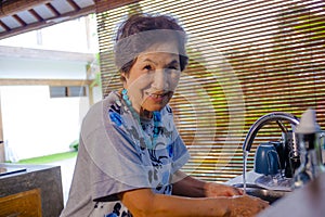 lifestyle portrait of senior happy and sweet Asian Japanese retired, woman cooking at home kitchen alone neat and tidy