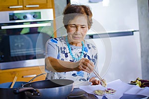 lifestyle portrait of senior happy and sweet Asian Japanese retired woman cooking at home kitchen alone neat and tidy