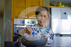 Lifestyle portrait of senior happy and sweet Asian Japanese retired woman cooking at home kitchen alone neat and tidy