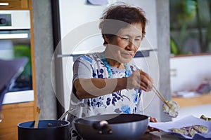 lifestyle portrait of senior happy and sweet Asian Japanese retired, woman cooking at home kitchen alone neat and tidy enjoying p