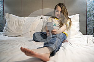 lifestyle portrait of sweet happy and beautiful 7 years old child having fun playing internet game with mobile phone