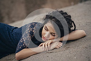 Lifestyle portrait of a woman brunette on background of the lake lying in sand on a cloudy day. Romantic, gentle, mystical