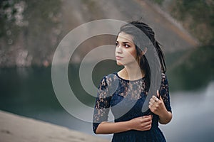 Lifestyle portrait of a woman brunette on the background of the lake in the sand on a cloudy day. Romantic, gentle, mystical