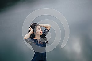 Lifestyle portrait of a woman brunette on the background of the lake in the sand on a cloudy day. Romantic, gentle, mystical