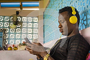 Lifestyle portrait of young attractive and cool hipster black afro American man using mobile phone and headset networking on