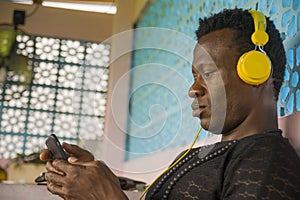 Lifestyle portrait of young attractive and cool hipster black afro American man using mobile phone and headset networking on