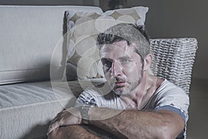 Lifestyle portrait young attractive sad and depressed man sitting on living room floor feeling desperate and stressed suffering