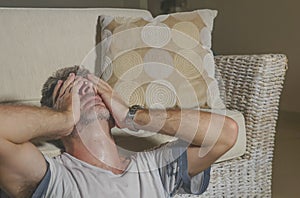 Lifestyle portrait young attractive sad and depressed man sitting on living room floor feeling desperate and stressed suffering