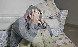 Lifestyle portrait young attractive sad and depressed man sitting on living room floor feeling desperate and stressed suffering