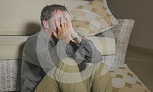 Lifestyle portrait young attractive sad and depressed man sitting on living room floor feeling desperate and stressed suffering