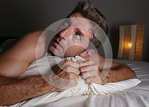 Lifestyle portrait of young attractive scared and paranoid man lying in bed having  bad dreams and nightmares looking around in