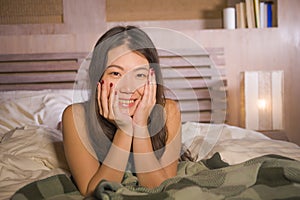 Lifestyle portrait of young beautiful and happy Asian Chinese woman lying in bed at home bedroom smiling cheerful and relaxed posi