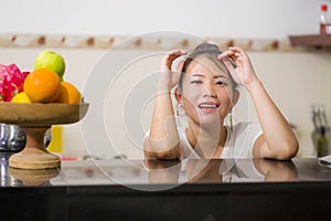 Lifestyle portrait of young beautiful and happy Asian Chinese woman posing relaxed at home kitchen smiling cheerful and sweet