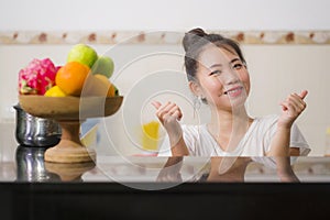 Lifestyle portrait of young beautiful and happy Asian Chinese woman posing relaxed at home kitchen smiling cheerful and sweet